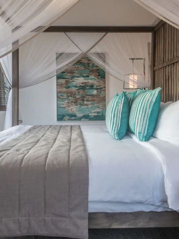 Himmelbett mit weißen Vorhängen und türkisfarbenen Akzenten