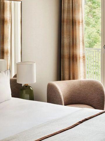 Helles Zimmer mit Balkon und stilvoller Einrichtung mit Aussicht auf Grün.