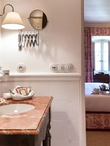 Badezimmer mit Marmorwaschbecken und Blick in ein elegantes Schlafzimmer.