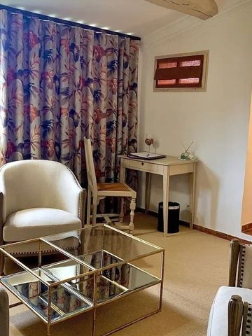 Gemütliches Wohnzimmer mit bequemen Sesseln und Glastisch vor bunten Vorhängen