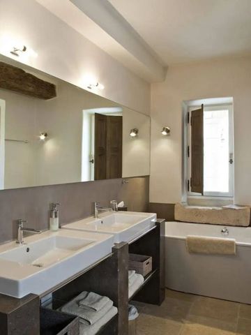 Badezimmer mit zwei Waschbecken, Badewanne und eleganter Beleuchtung.