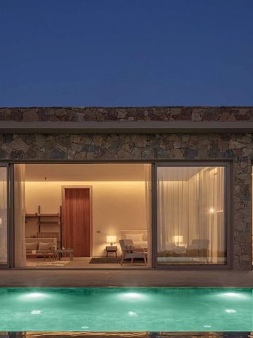 Moderne Villa mit großen Fenstern und beleuchtetem Pool bei Nacht