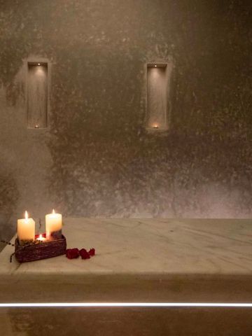 Wellnessraum mit Kerzen und Massagebett in gedämpftem Licht