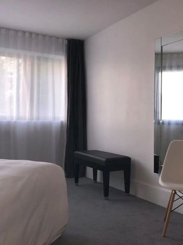 Helles Zimmer mit Teppichboden, Bett, Stuhl und Spiegel im La Maison Champs Elysées.