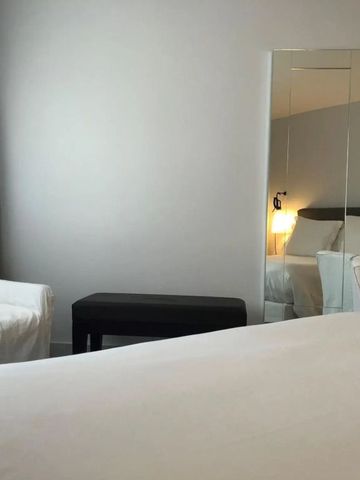 Schlafzimmer mit Bett, Spiegel, Nachttischlampe und Sessel im Hotelzimmer.