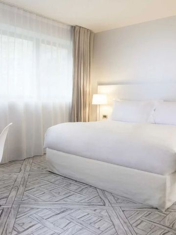 Geräumiges Zimmer mit modernem Teppich, Bett und Sitzgelegenheit.