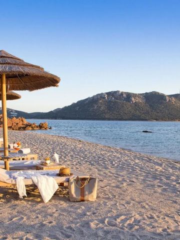 Strand mit Liegestühlen und Sonnenschirmen unter blauem Himmel