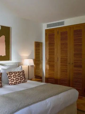 Elegantes Schlafzimmer mit Kunstwerk über dem Bett und Holzschrank.