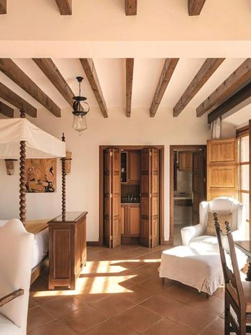 Helles Hotelzimmer mit Himmelbett und Holzbalken