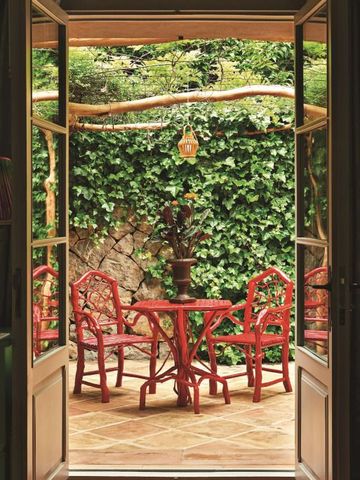 Gemütliche Terrasse mit roten Stühlen und grüner Wandbewachsung