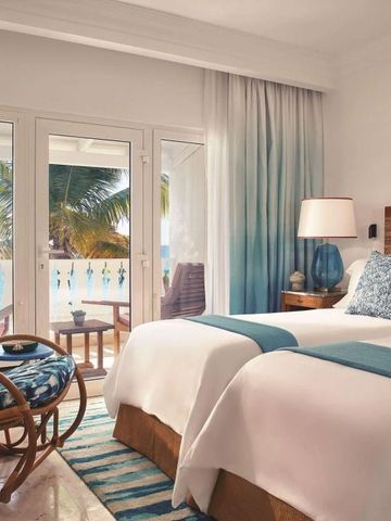 Helles Zimmer mit zwei Betten, Balkonblick auf Palmen und Ozean