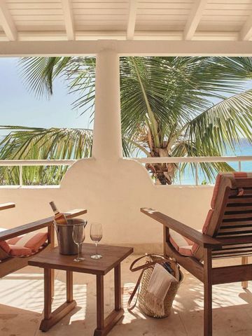 Balkon mit Holzstühlen und Tisch mit Blick auf Palmen und Meer