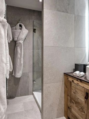 Modernes Badezimmer mit eleganten Natursteinfliesen und großem Spiegel.