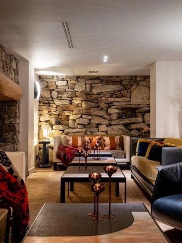 Gemütlicher Sitzbereich mit Natursteinwand und modernen Sofas