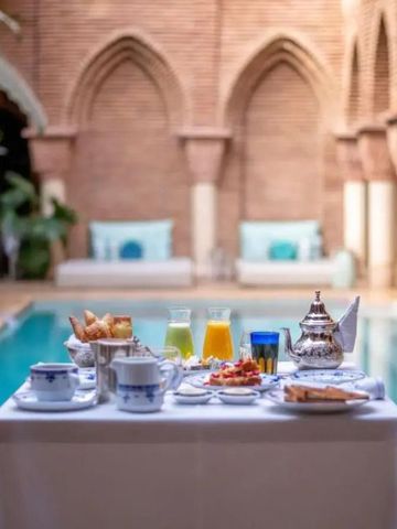 Frühstückstisch mit Tee und Gebäck am Pool in marokkanischem Ambiente