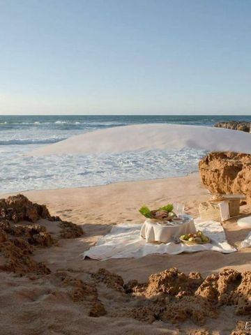 Strandsetup mit Sonnenschutz und Picknick bei Sonnenuntergang an der Küste von Oualidia