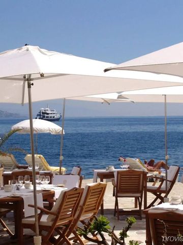 Elegante Strandterrasse mit Tischen und weißen Sonnenschirmen am Meer