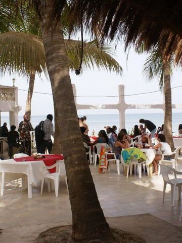Terrasse mit Palmen und Gästen mit Meerblick.