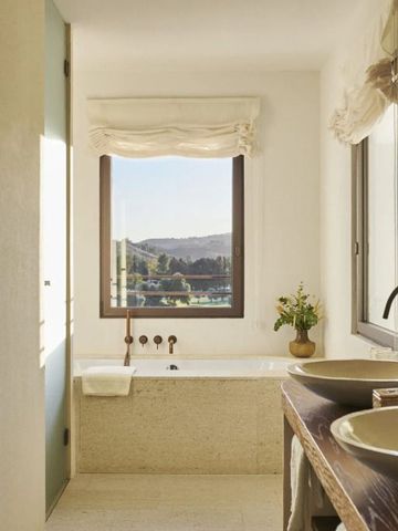 Helles Badezimmer mit großer Badewanne und Aussicht auf die Landschaft