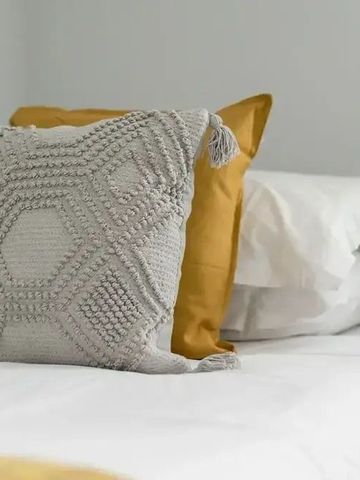 Gemütliches Bett mit dekorativen Kissen in neutralem Farbton