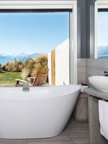 Luxuriöses Badezimmer mit freistehender Badewanne und spektakulärer Aussicht auf den See