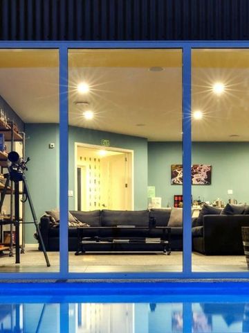 Blick auf modernen Wohnbereich durch große Fenster mit Pool im Vordergrund