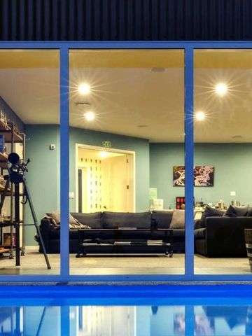 Blick auf modernen Wohnbereich durch große Fenster mit Pool im Vordergrund