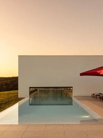 Infinity Pool mit Sonnenliegen und Sonnenschirmen bei Sonnenuntergang