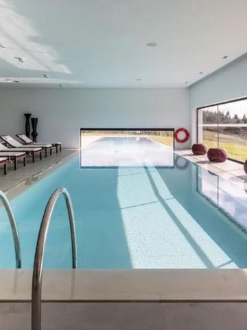 Innenpool mit Liegestühlen und Panoramafenster, das eine ländliche Aussicht bietet