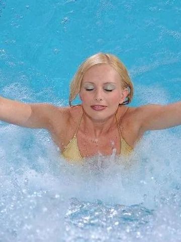 Frau genießt sprudelndes Wasser im Pool