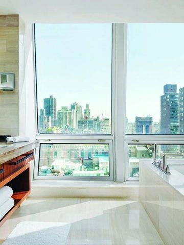 Helles Badezimmer mit Badewanne und Panoramablick auf die Stadt.