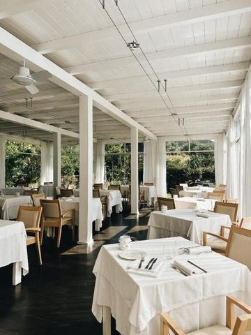 Eleganter Speisesaal mit weißen Tischdecken und großen Fenstern