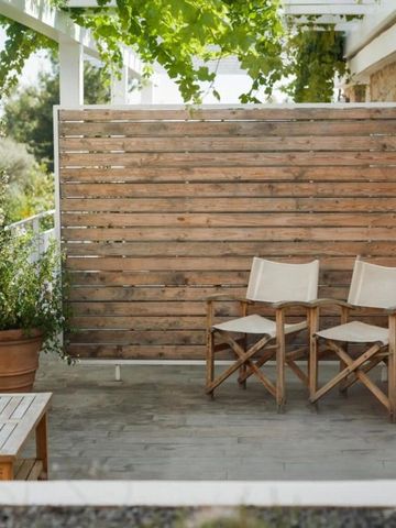 Holzterrasse mit Naturmöbeln und grüner Umrahmung