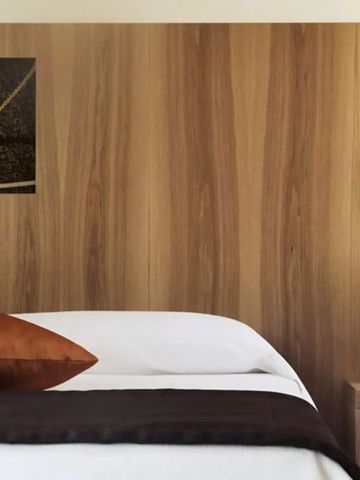 Schlafbereich mit Holzvertäfelung und stilvoller Beleuchtung.