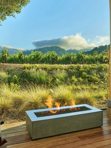Terrasse mit Freiluftkamin und Blick auf grüne Weinberge und Hügel.
