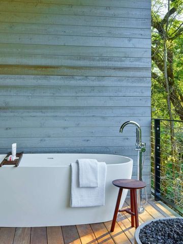 Freistehende Badewanne auf einer Terrasse mit Waldblick