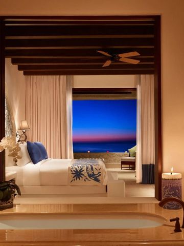 Luxuriöses Schlafzimmer mit Blick auf den Ozean bei Sonnenuntergang und stilvoller Einrichtung.