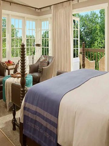 Elegantes Schlafzimmer mit großem Fenster und schöner Aussicht auf grüne Landschaft