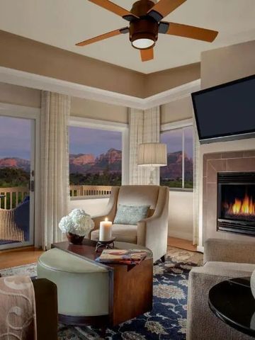 Wohnzimmer mit Kamin und Panoramafenster mit Blick auf rot gefärbte Berge