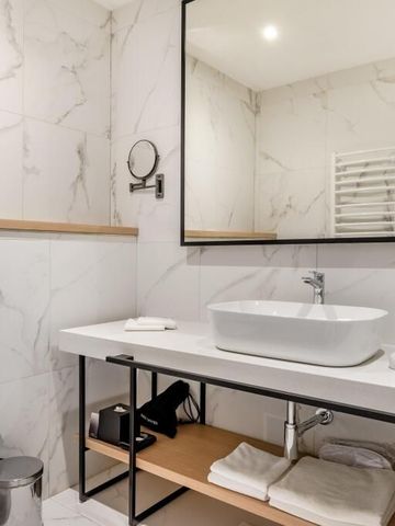 Moderne Badausstattung mit weißem Waschtisch und Marmordesign.