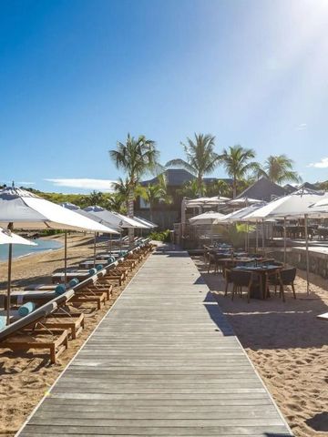 Holzsteg entlang des Strandes mit Liegen und Sonnenschirmen