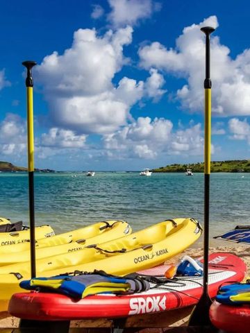 Kajaks und Paddleboards am Strand mit Blick auf das Meer