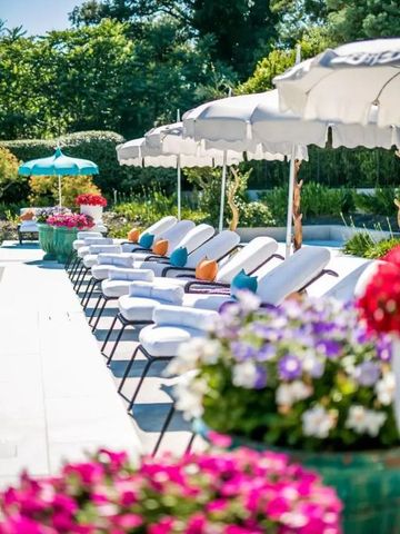 Sonnenliegen am Pool mit Sonnenschirmen und blühenden Blumen im Garten.