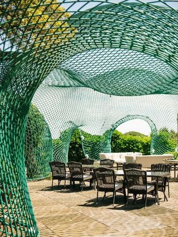 Moderne Sitzgruppe unter einem stilvollen Netz-Pavillon im Garten.