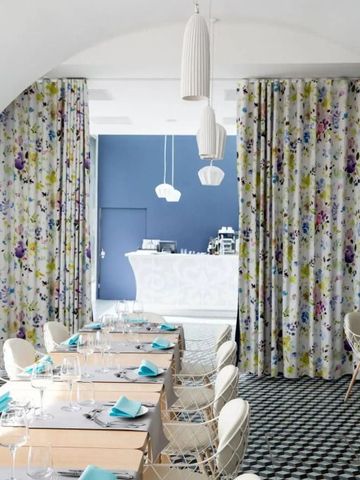 Eleganter Speiseraum mit floralen Vorhängen und gedecktem Tisch