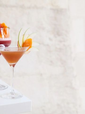 Zwei elegante Cocktails vor heller Steinwand