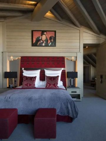 Luxuriöses Schlafzimmer mit Holzbalkendecke und eleganten roten Akzenten