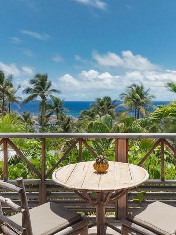 Blick von einer Terrasse auf Palmen und das Meer mit blauen Himmel