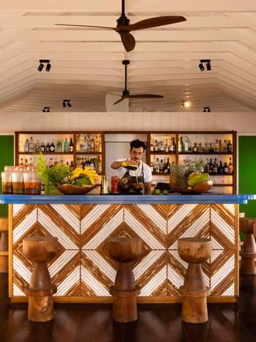 Stilvolle Bar aus Holz mit bunten Getränken und Bartender