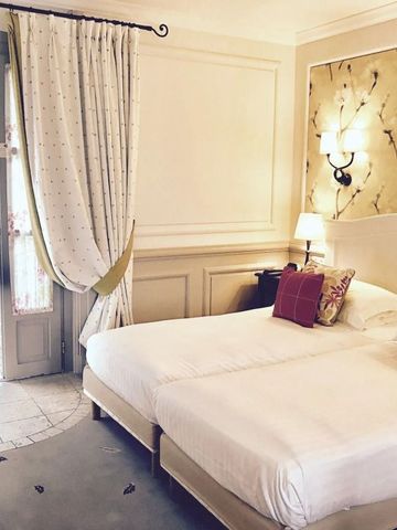 Helles Hotelzimmer mit zwei Einzelbetten und blumiger Tapete